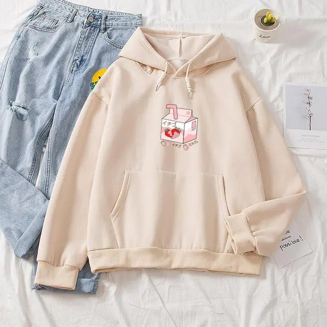 Beige hoodie with a cartoon design on a white surface with jeans and a card.