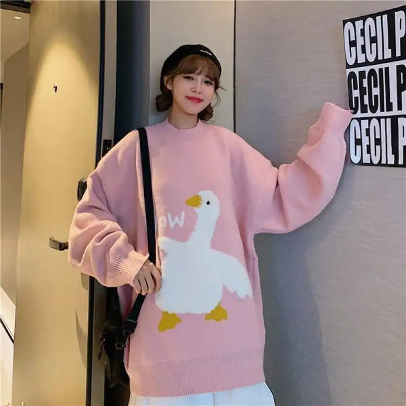 Person wearing a pink sweater with a cartoon duck design, standing indoors.
