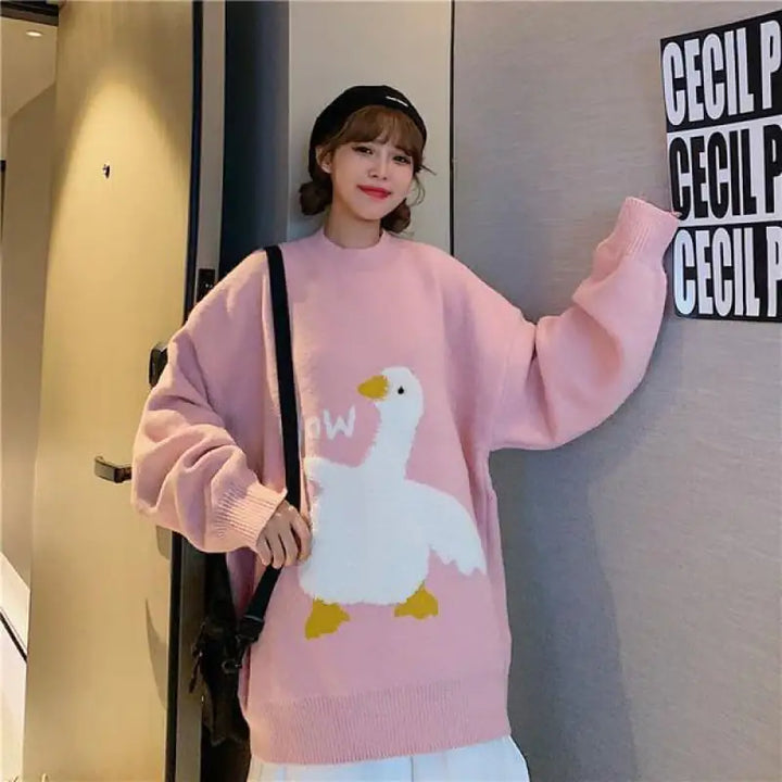Person wearing a pink sweater with a cartoon duck design, standing indoors.