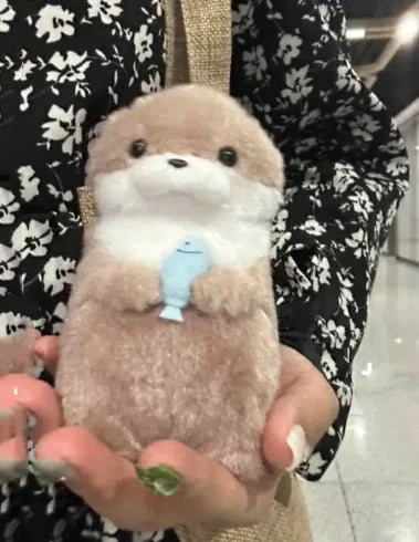 Plush toy resembling a bear held in hands with a blurred background