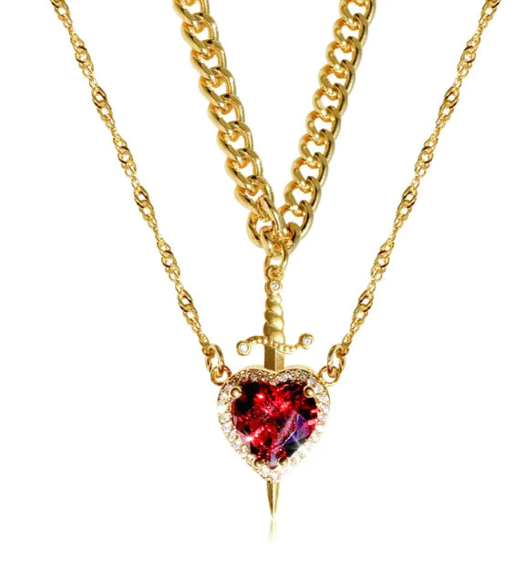 Gold necklace with a heart-shaped red gemstone pendant on a white background