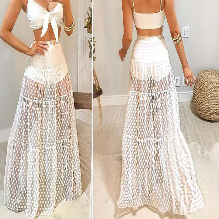 Woman wearing a white two-piece outfit with a long skirt in a room.