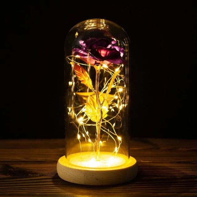 Decorative lamp with a glass dome containing a rose and LED lights on a wooden base.