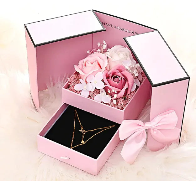 Pink gift box with flowers and a necklace on a light background